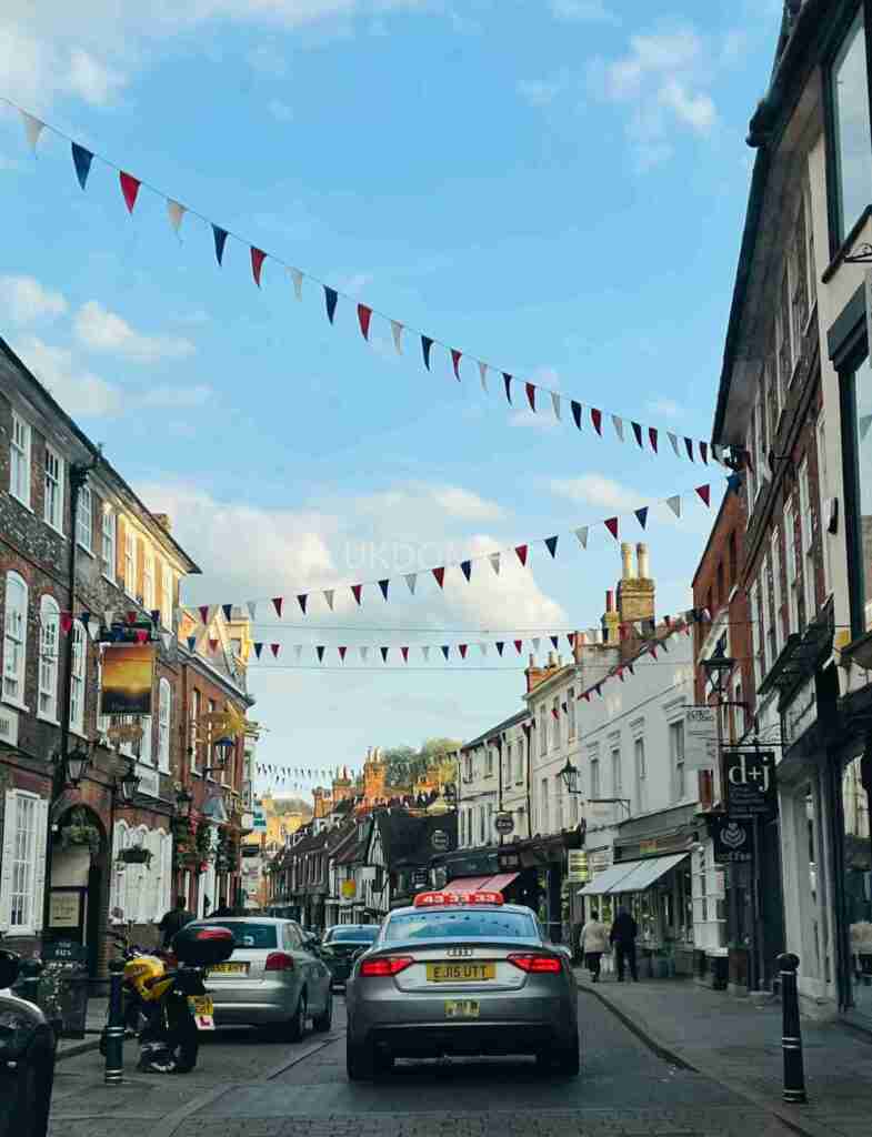 Vibrant street view with cars and flags in Hertfordshire, England on a sunny day.