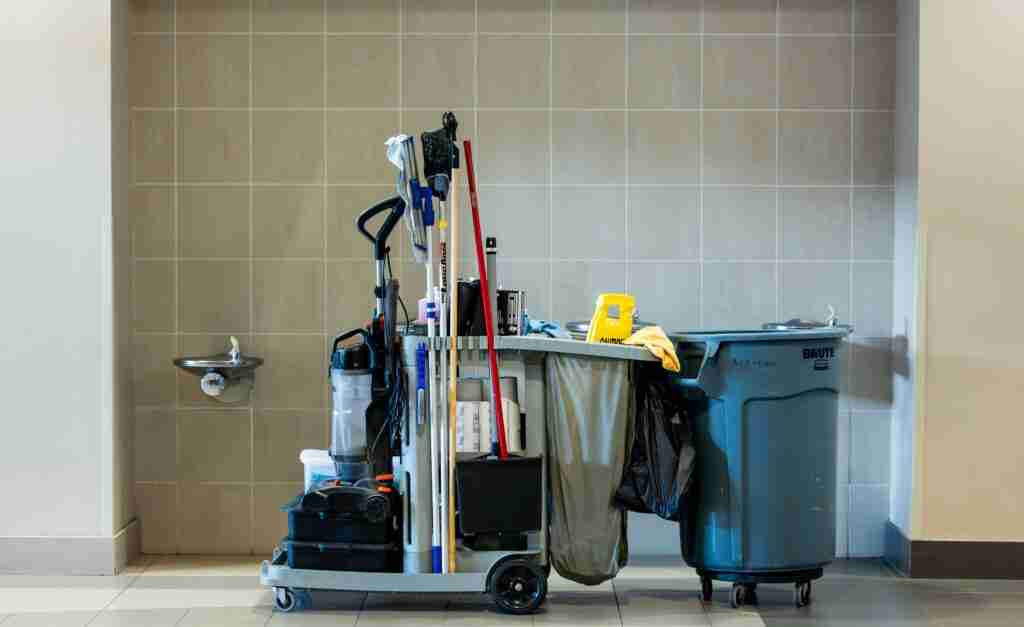 A comprehensive collection of professional cleaning tools on a cart in an indoor environment.